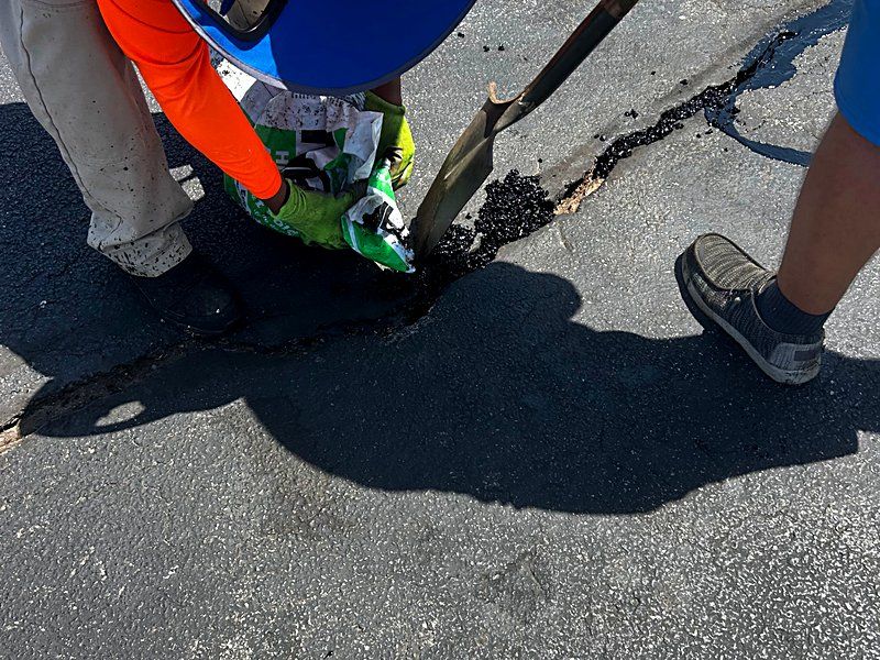 Crew hand-working an asphalt repair on a commercial parking lot