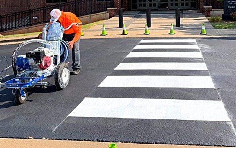 Heartland crew member operating a striping machine over a freshly painted crosswalk